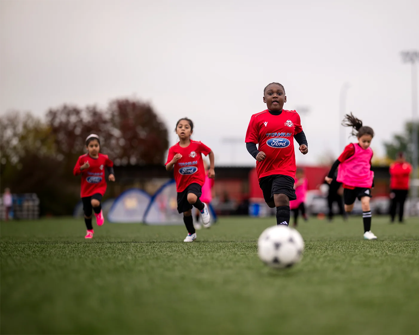 Youth soccer players running toward the ball during practice