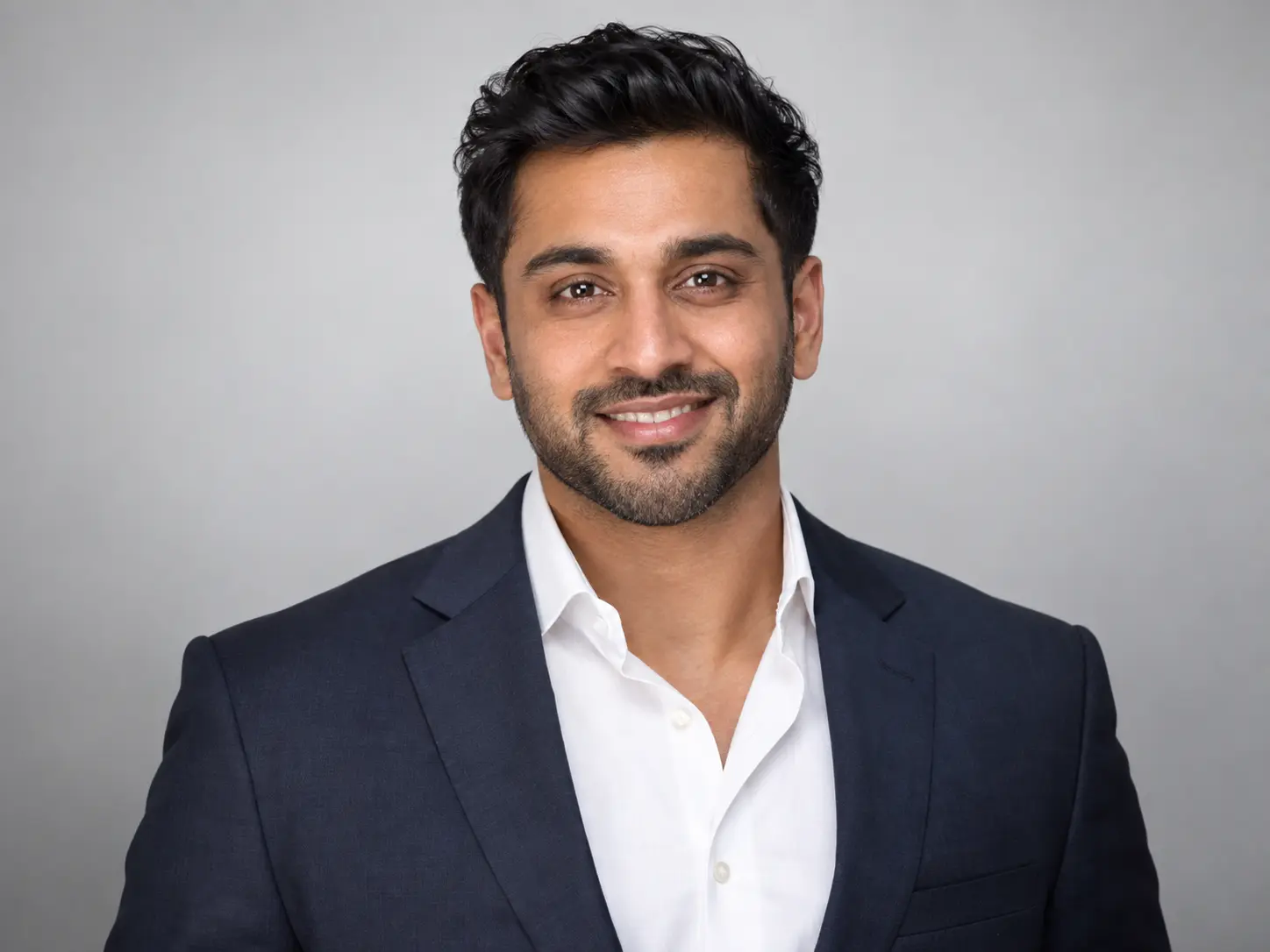 Professional corporate headshot of a man in a navy blazer